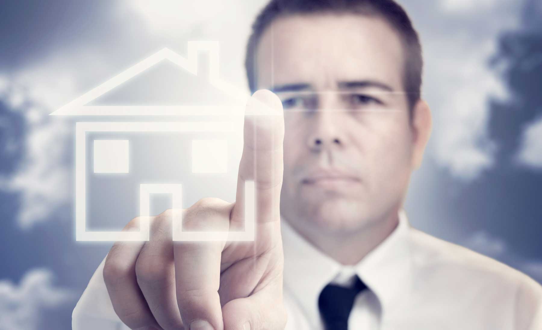 gravámenes-embargos Hombre con una foto de una casa en la pantalla de su computadora